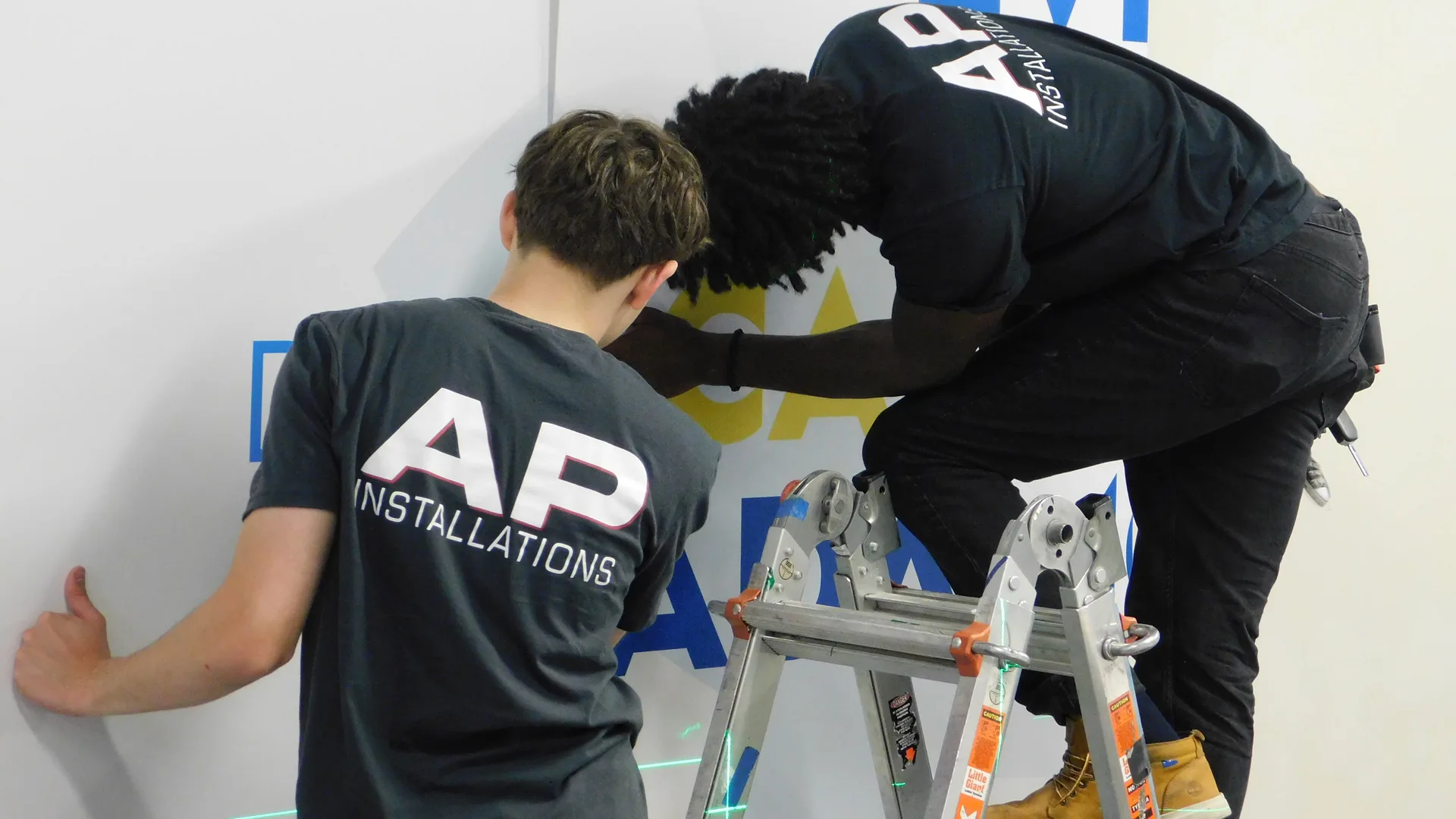 Uniformed AP Installations crew installing large-format wall graphics