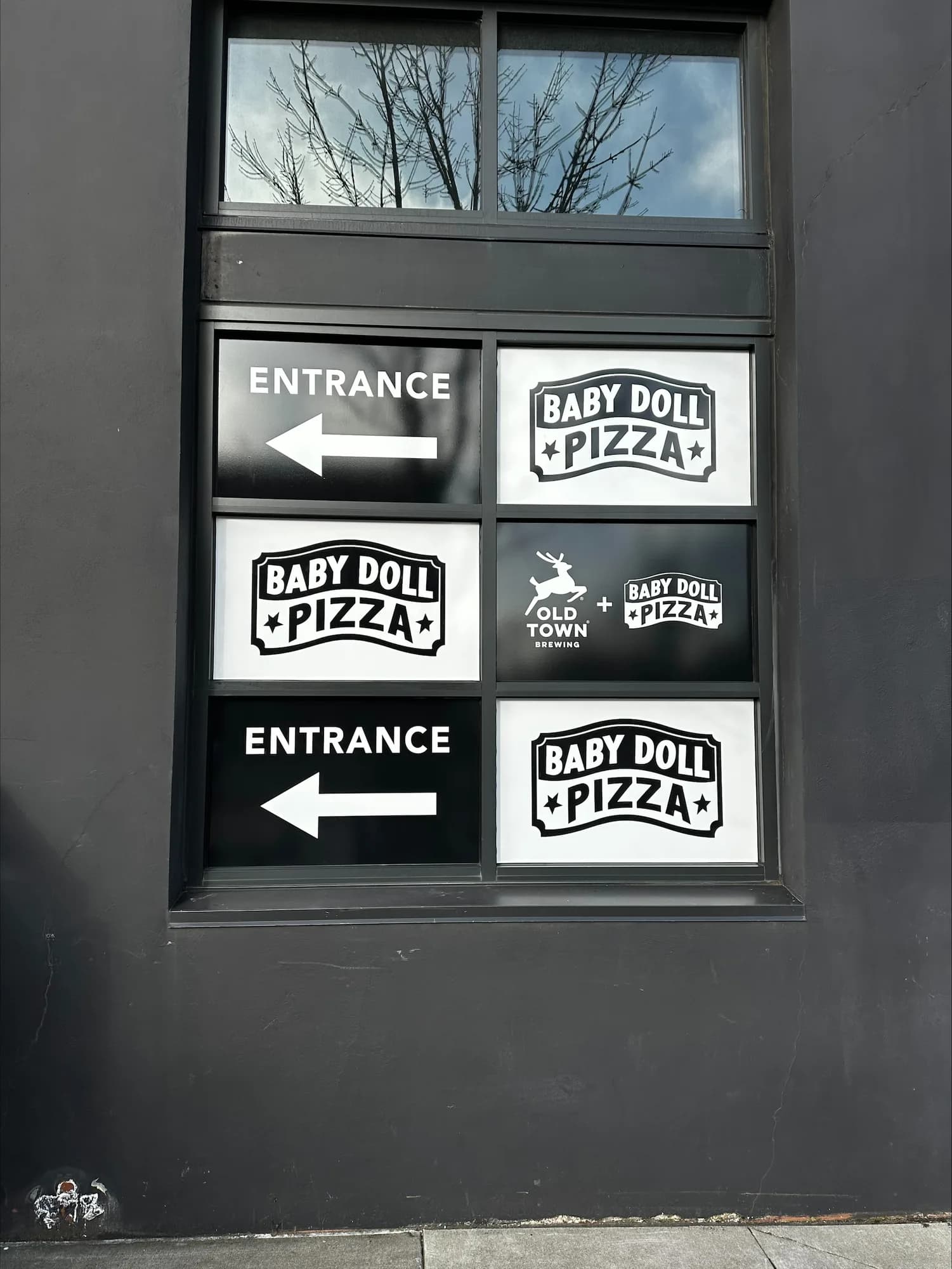 Baby Doll Pizza entrance and wayfinding graphics on a storefront window